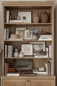 a wooden bookcase filled with books and pictures