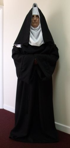 a man dressed in a nun costume standing next to a wall