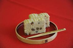 two pieces of cake on a plate with chopsticks next to it and a red background