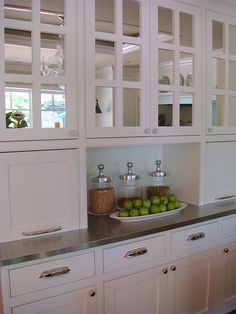 a kitchen with white cabinets and stainless steel counter tops, including apples on a plate