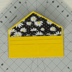 a piece of fabric sitting on top of a ruler next to a yellow envelope with black and white flowers