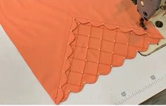 an orange piece of cloth is being sewn