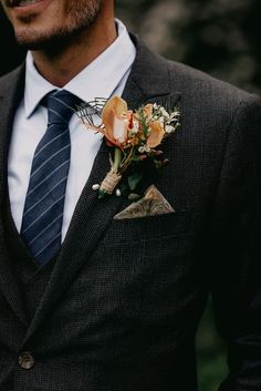 a man wearing a suit and tie with a boutonniere on his lapel