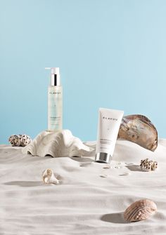 a bottle of lotion sitting on top of a bed next to shells and seashells