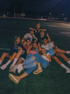 a group of young people sitting on top of each other in the middle of a field