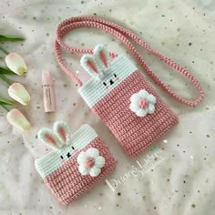 two crocheted purses sitting on top of a bed next to tulips