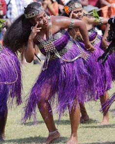 two women in purple hula skirts are dancing