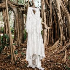 a white dress hanging from a tree in the woods