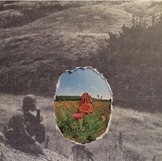 an old photo of a soldier sitting on a hill with a red flower in the foreground