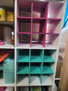 the shelves have many different colored bins on them, and one shelf is empty