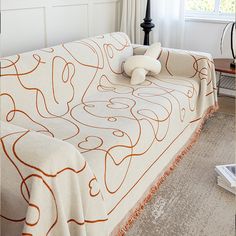 an orange and white couch in a living room next to a table with a lamp on it