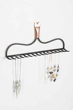 a metal rack with several necklaces hanging from it's sides and an earring holder attached to the wall