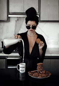 a woman pouring milk into a cup next to cookies