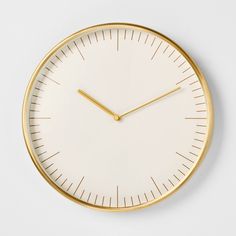 a white clock with gold hands on a white wall