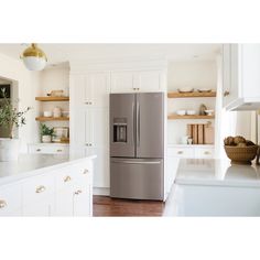 a silver refrigerator freezer sitting inside of a kitchen next to white counter tops and cabinets