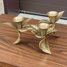 three brass candlesticks sitting on top of a wooden table