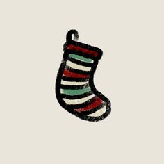 a christmas stocking hanging from the side of a white wall with red, green and black stripes