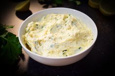 a white bowl filled with mashed potatoes on top of a table next to lemon wedges