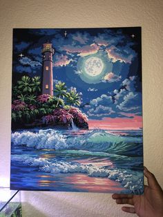 a person holding up a painting in front of a wall with a light house on it