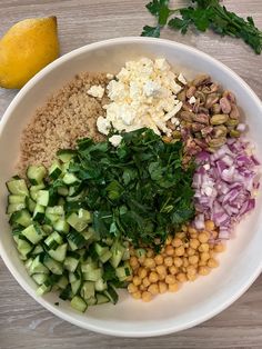 a white bowl filled with different types of food on top of a wooden table next to a lemon