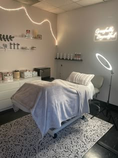 a white bed sitting in a bedroom next to a wall with lights hanging above it