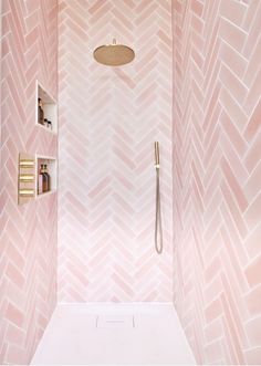 a bathroom with pink and white wallpaper, gold fixtures and a walk in shower