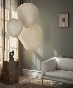 three white lanterns hanging from the ceiling in a living room next to a couch and chair