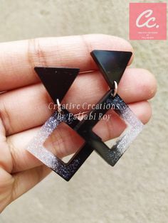 a pair of black and white earrings in the shape of an inverted triangle, with glittery accents