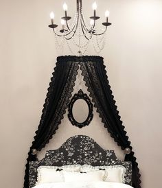 a black and white bed with a chandelier hanging over it's headboard