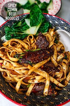 a bowl filled with noodles and meat on top of a white table next to greens