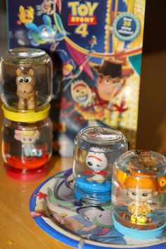 three toys are sitting on a table next to a toy story book and other items