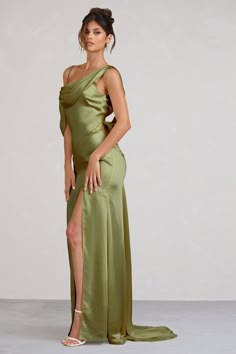 a woman in a green dress posing for the camera with her leg slited up