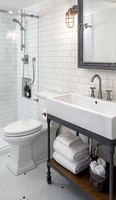 a white toilet sitting next to a sink in a bathroom under a mirror and shower