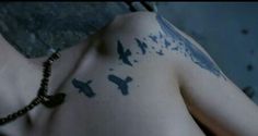 a man with tattoos on his chest and birds painted on the back of his body