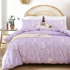 a bed with purple comforter and pillows in a room