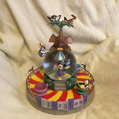 the figurine is sitting on top of the toy fairground carousel with mickey mouse and other characters