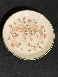 a white plate with pink flowers and a bow on the rim is sitting on a black surface