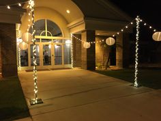 an entrance to a building with lights on the walkway and lanterns hanging from it's sides