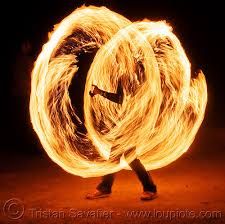 a person is spinning a fire ring around their body in the dark with one hand