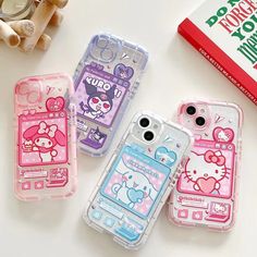 three cell phones with hello kitty designs on them sitting next to a book and some other items