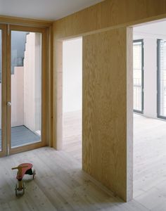 an empty room with wooden walls and sliding glass doors on the outside, and a toy bench in the middle