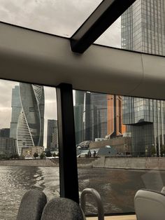 the interior of a bus looking out over water and skyscrapers in the background,