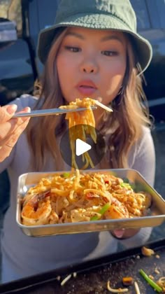 a woman is eating noodles with chopsticks in her hand