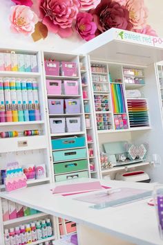 a craft room with lots of crafting supplies and flowers on the wall above it