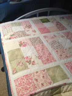 a bed with a pink and green quilt on it