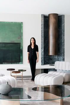 a woman is standing in the middle of a room with modern furniture and art on the walls