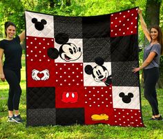 two women holding up a mickey mouse quilt