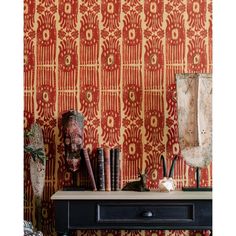 a table with books and vases on it in front of a wallpapered background