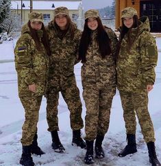 three women in camouflage uniforms posing for a photo together on the snow covered ground with their arms around each other