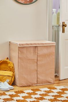 a brown storage box sitting on top of a wooden floor next to a yellow backpack